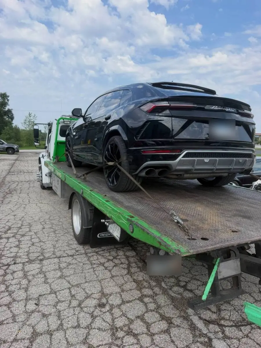 Black Lamborghini Urus strapped down on a PS Towing flatbed