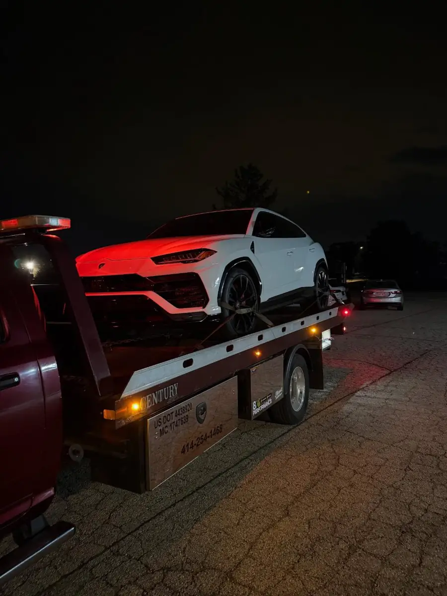 White Lamborghini Urus loaded on a PS Towing flatbed at night