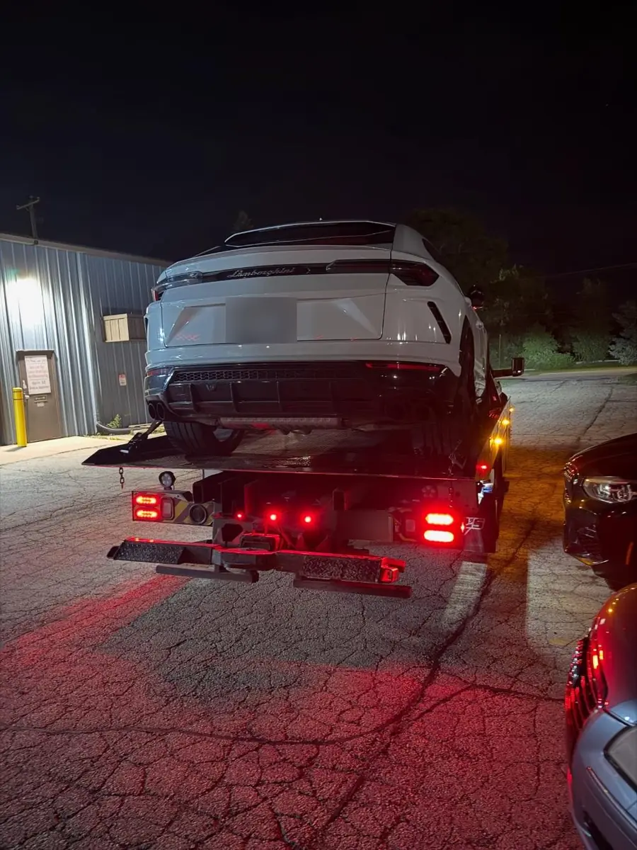 Rear view of a white Lamborghini Urus loaded for transport