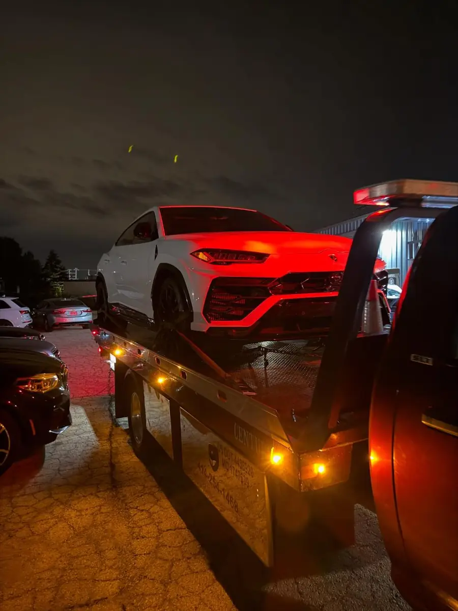 PS Towing truck at night with a Lamborghini Urus on the flatbed