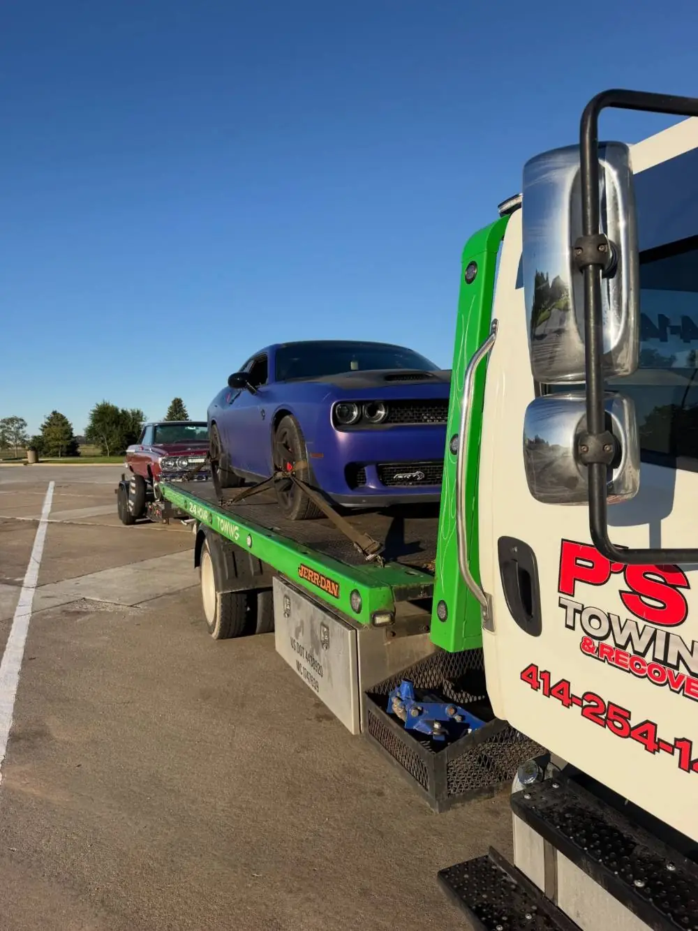 PS Towing flatbed truck hauling a purple Dodge Challenger